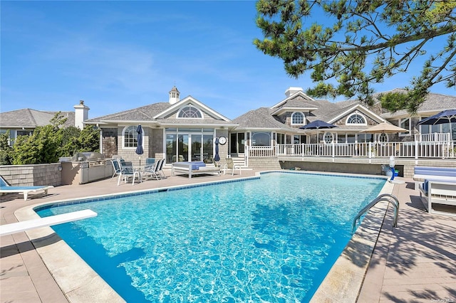 view of swimming pool with a patio area, a diving board, exterior kitchen, and a grill