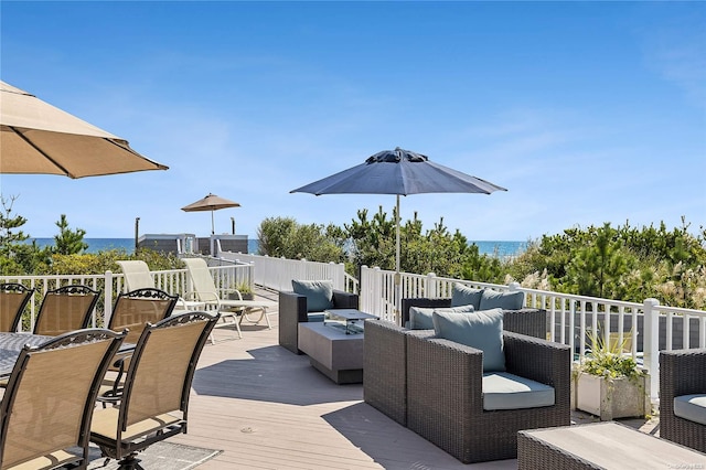 wooden deck with a water view and an outdoor living space with a fire pit