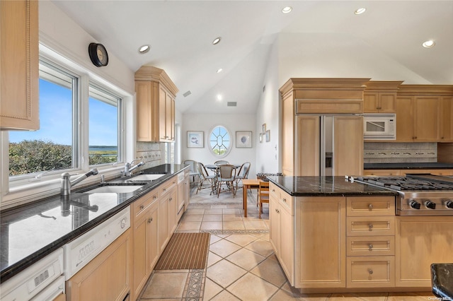 kitchen with dark stone counters, sink, built in appliances, tasteful backsplash, and light tile patterned flooring