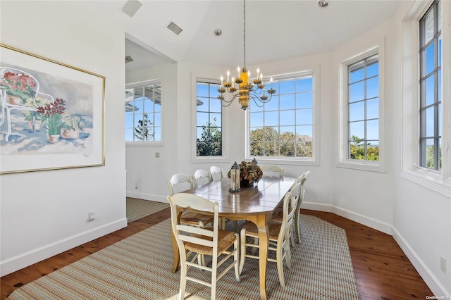 dining room with a wealth of natural light, dark hardwood / wood-style flooring, and an inviting chandelier