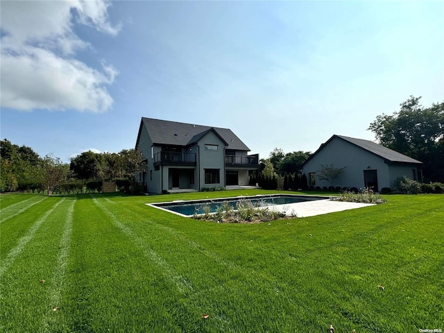 rear view of property featuring a balcony and a yard