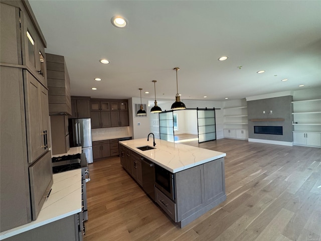 kitchen featuring light stone countertops, stainless steel appliances, sink, hanging light fixtures, and a large island