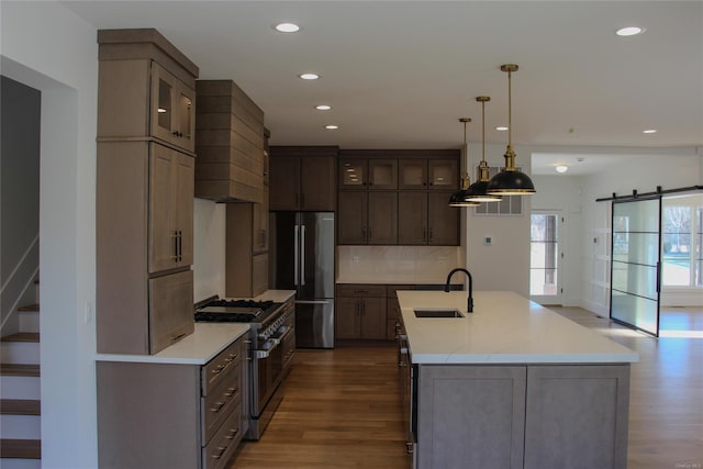 kitchen featuring pendant lighting, appliances with stainless steel finishes, hardwood / wood-style floors, premium range hood, and light stone counters