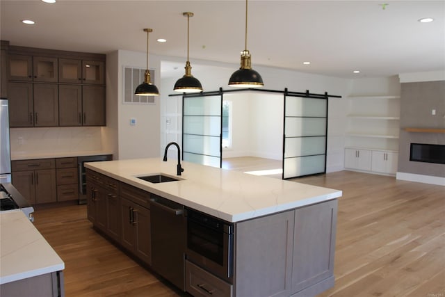 kitchen featuring light stone countertops, a barn door, dishwasher, and sink