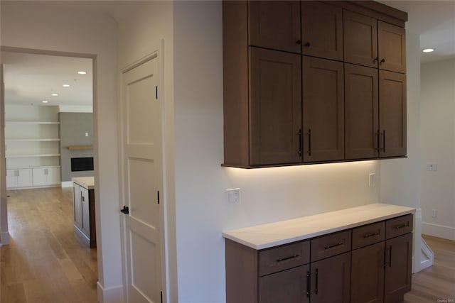 kitchen featuring built in features, light hardwood / wood-style floors, and dark brown cabinetry