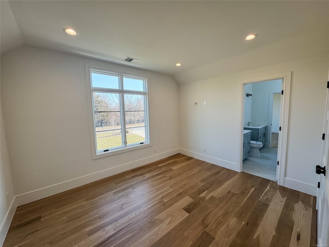 interior space with ensuite bathroom, wood-type flooring, and lofted ceiling