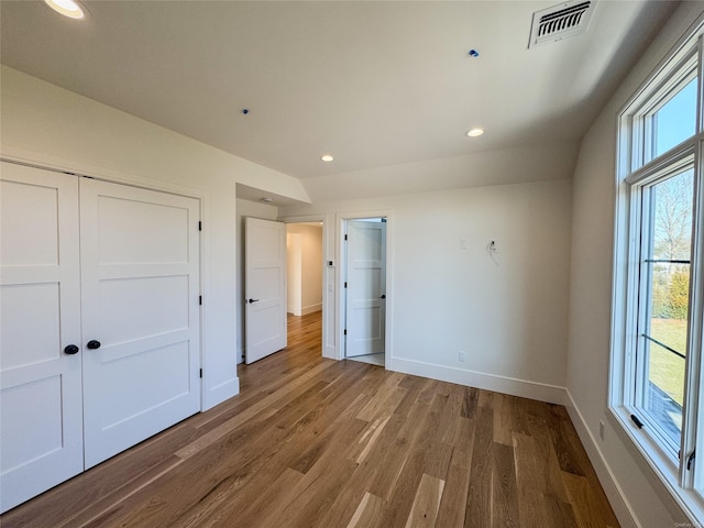 unfurnished bedroom with vaulted ceiling, a closet, and hardwood / wood-style floors