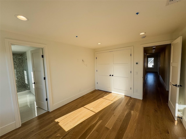 unfurnished bedroom with dark wood-type flooring and a closet