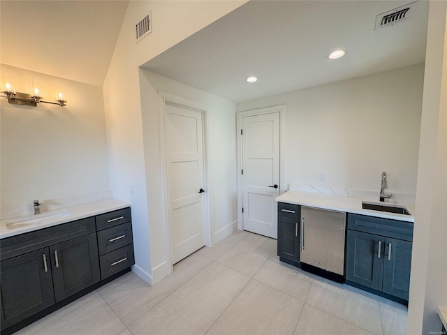 bar with light tile patterned floors, light stone countertops, and sink