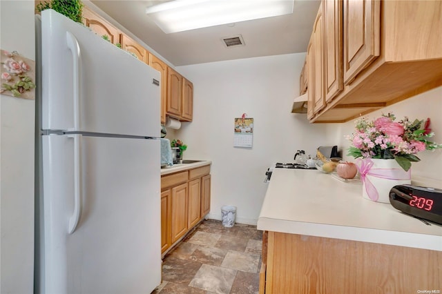 kitchen featuring light brown cabinets and white fridge