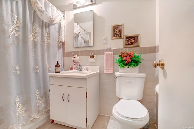 full bathroom featuring toilet, vanity, tile patterned floors, and tile walls