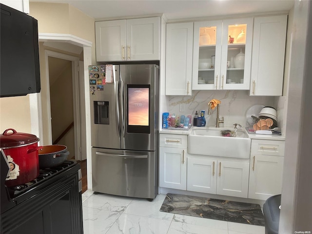 kitchen featuring tasteful backsplash, stainless steel fridge, sink, and white cabinets