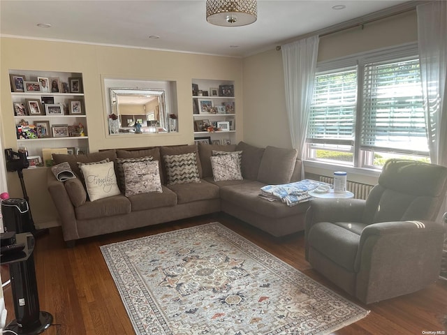 living room featuring built in shelves, dark hardwood / wood-style floors, and crown molding