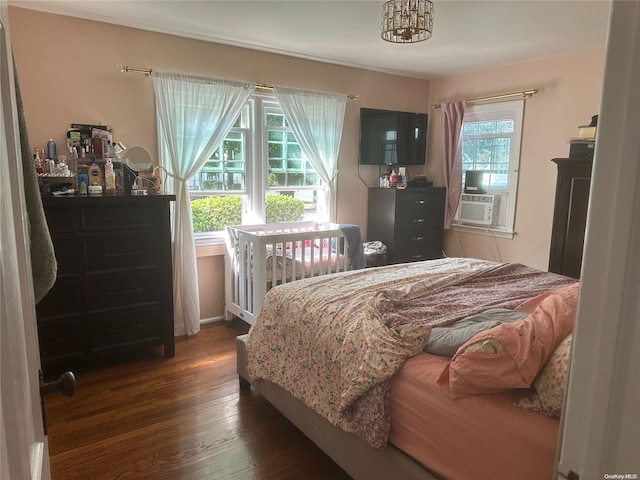 bedroom with cooling unit, dark hardwood / wood-style floors, an inviting chandelier, and multiple windows