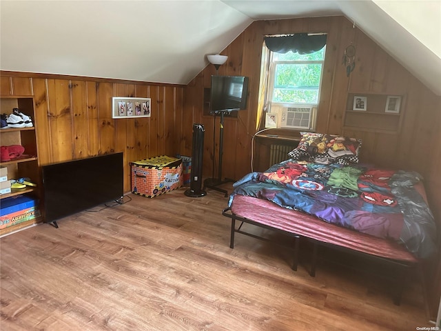 bedroom featuring lofted ceiling, cooling unit, light wood-type flooring, and wooden walls