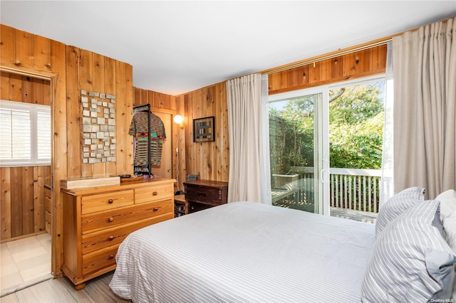 bedroom with wood walls, access to outside, and multiple windows