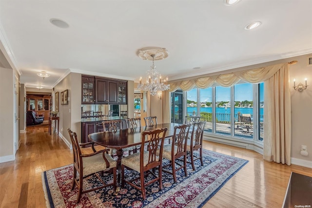 dining area with light hardwood / wood-style floors, a water view, crown molding, and a chandelier