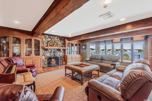 living room with beamed ceiling, hardwood / wood-style floors, a water view, and a fireplace