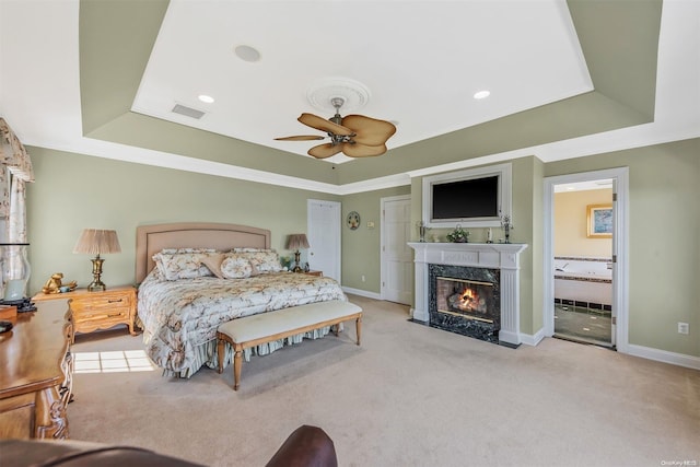 bedroom with ceiling fan, light carpet, and a tray ceiling