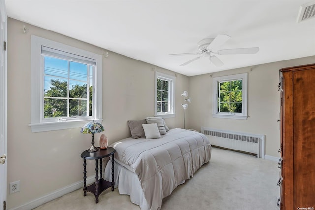 carpeted bedroom with ceiling fan and radiator