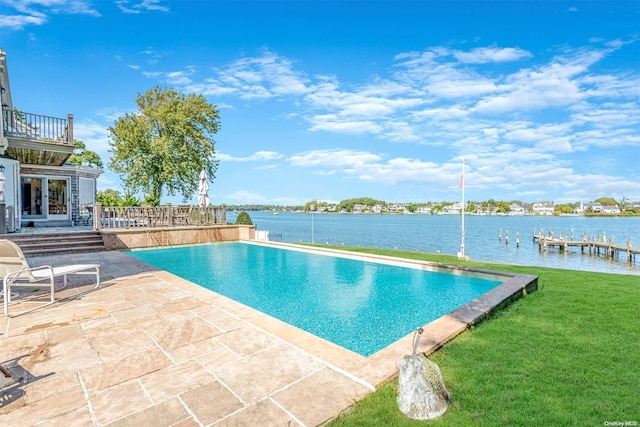 view of pool featuring a lawn, a water view, and a patio