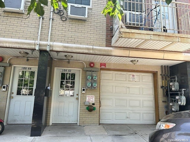 property entrance with a balcony, cooling unit, and a garage