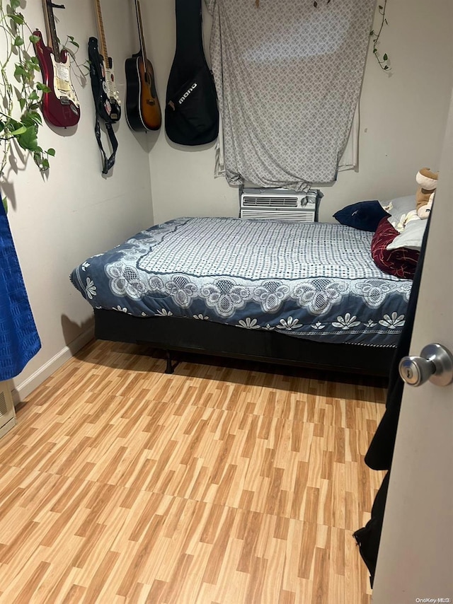 bedroom with wood-type flooring and an AC wall unit