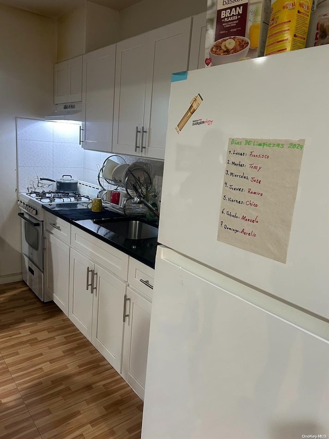 kitchen featuring white fridge, white cabinetry, light hardwood / wood-style flooring, and range with gas cooktop