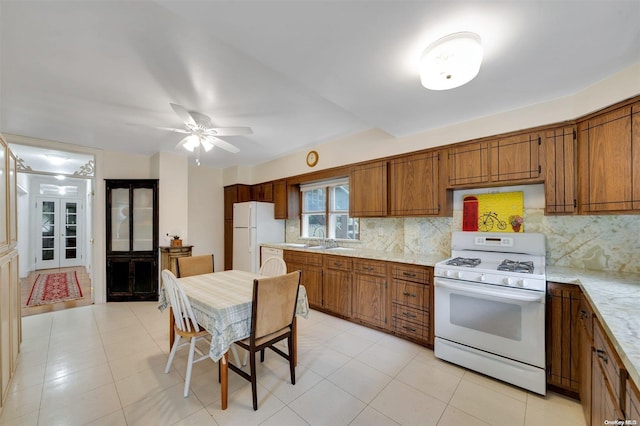 kitchen featuring tasteful backsplash, white appliances, ceiling fan, sink, and light tile patterned floors