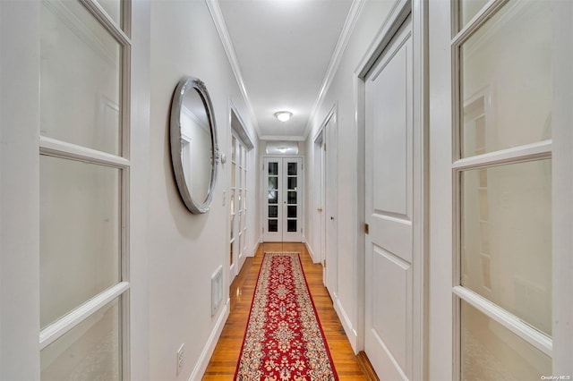 hall featuring french doors, light wood-type flooring, and ornamental molding