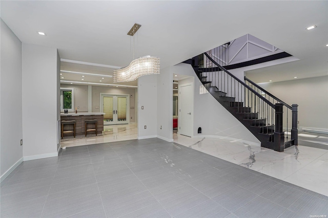 unfurnished living room featuring french doors and an inviting chandelier