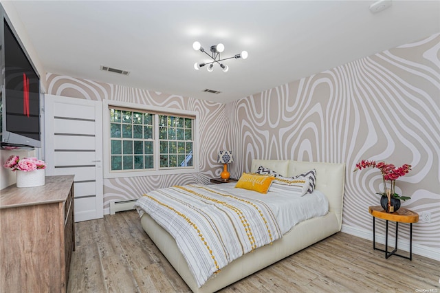 bedroom featuring an inviting chandelier, light hardwood / wood-style flooring, and baseboard heating