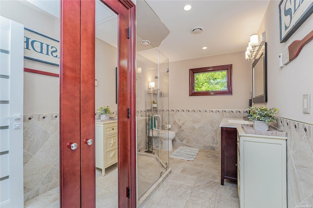 bathroom featuring vanity, a shower with door, tile walls, tile patterned flooring, and toilet