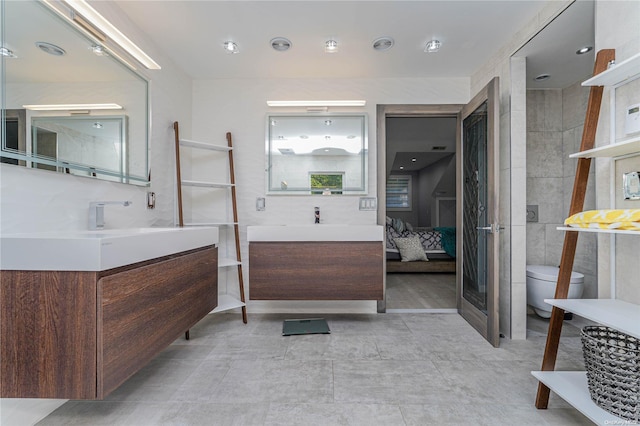 bathroom featuring vanity, toilet, and tile walls