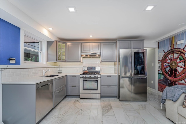 kitchen with tasteful backsplash, gray cabinetry, sink, and appliances with stainless steel finishes