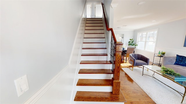 stairway featuring ornamental molding and wood finished floors