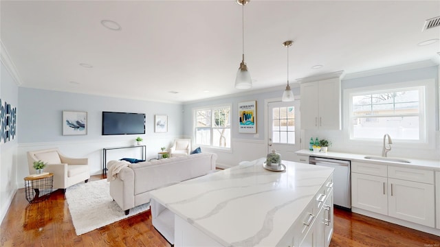 kitchen with wood finished floors, stainless steel dishwasher, a sink, and a center island