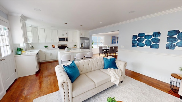 living area with a wealth of natural light, crown molding, and wood finished floors