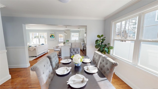 dining room with crown molding, baseboards, and wood finished floors