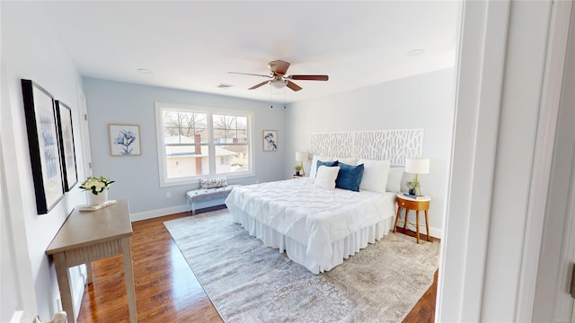 bedroom featuring a ceiling fan, visible vents, baseboards, and wood finished floors