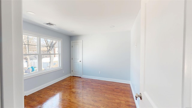 spare room with baseboards, visible vents, and wood finished floors