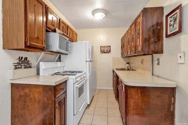 kitchen featuring white appliances, sink, and light tile patterned floors