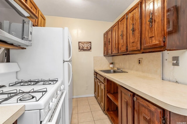 kitchen with light tile patterned floors, tasteful backsplash, white gas range, and sink