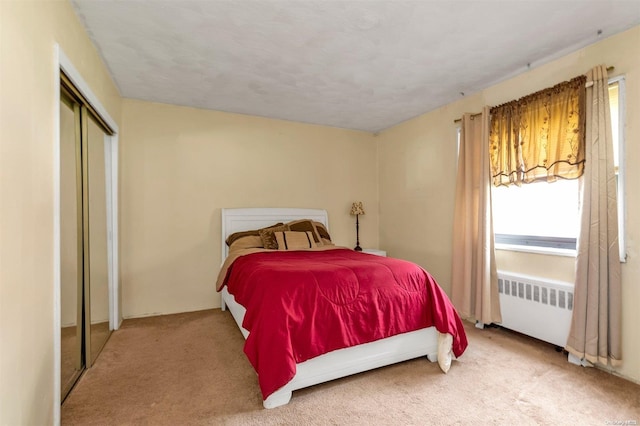 bedroom featuring a closet, radiator heating unit, and carpet