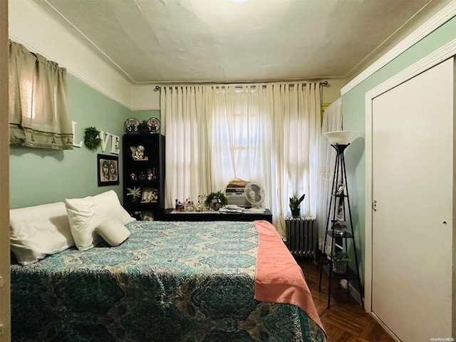 bedroom with radiator heating unit, dark parquet floors, and ornamental molding