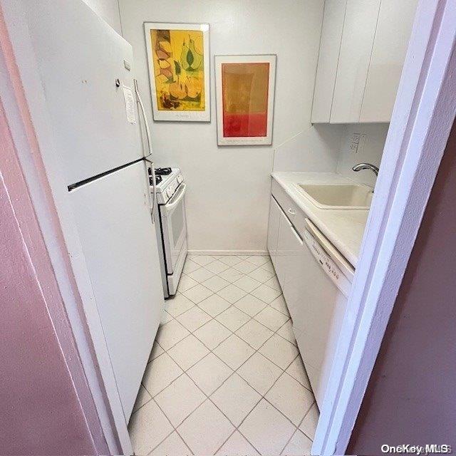 kitchen with white cabinets, light tile patterned floors, white appliances, and sink