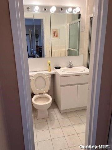 bathroom featuring toilet, tile patterned flooring, vanity, and walk in shower