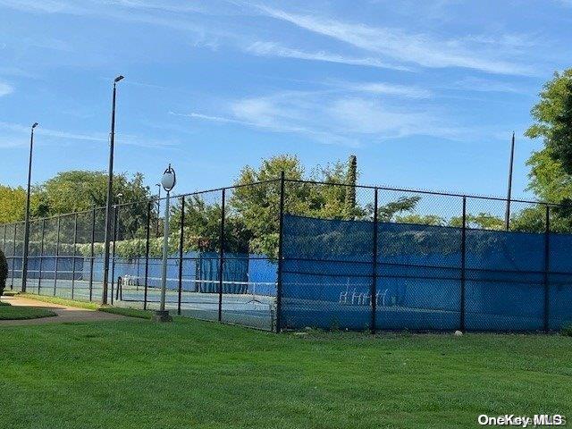 view of tennis court featuring a yard