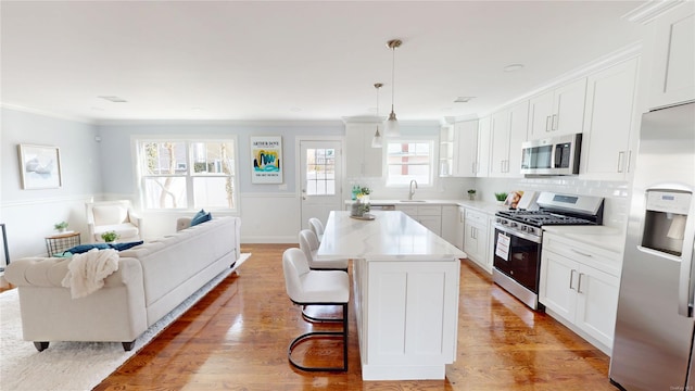 kitchen with light wood-style floors, tasteful backsplash, appliances with stainless steel finishes, and a sink