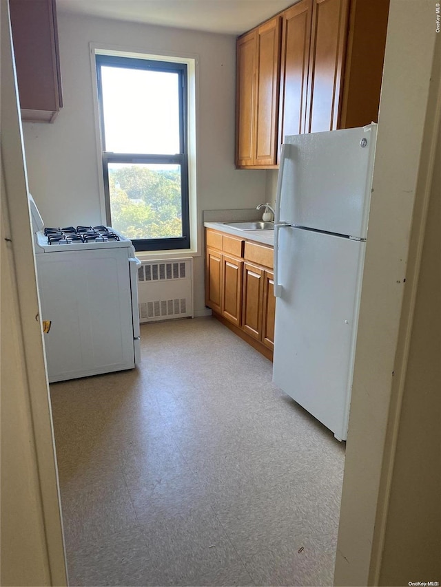 kitchen with white appliances, radiator, and sink